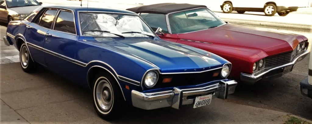 a blue Ford Maverick and a red Cadillac Eldorado Convertible