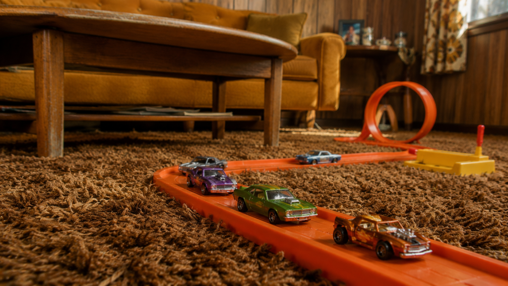 Die-cast toy cars racing on an orange 1970s track